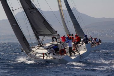 Bodrum, Türkiye. 14 Nisan 2018: Ünlü tatil beldesi Bodrum 'un kıyılarında, Ege Denizi' nin mavi sularında rüzgarlı havada yelken açan yelkenliler.