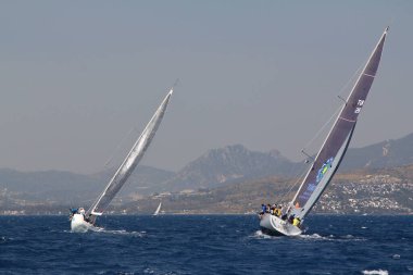 Bodrum, Türkiye. 14 Nisan 2018: Ünlü tatil beldesi Bodrum 'un kıyılarında, Ege Denizi' nin mavi sularında rüzgarlı havada yelken açan yelkenliler.