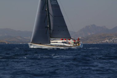 Bodrum, Türkiye. 14 Nisan 2018: Ünlü tatil beldesi Bodrum 'un kıyılarında, Ege Denizi' nin mavi sularında rüzgarlı havada yelken açan yelkenliler.