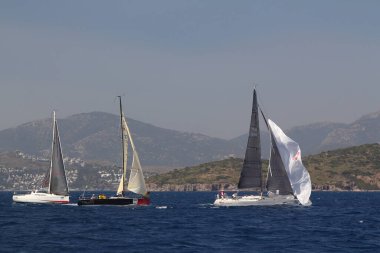 Bodrum, Türkiye. 14 Nisan 2018: Ünlü tatil beldesi Bodrum 'un kıyılarında, Ege Denizi' nin mavi sularında rüzgarlı havada yelken açan yelkenliler.