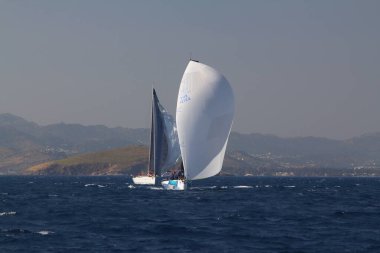 Bodrum, Türkiye. 14 Nisan 2018: Ünlü tatil beldesi Bodrum 'un kıyılarında, Ege Denizi' nin mavi sularında rüzgarlı havada yelken açan yelkenliler.
