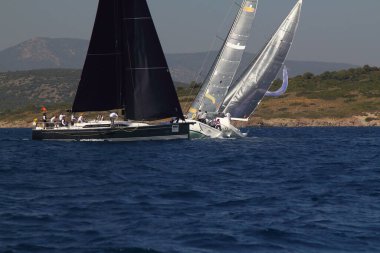 Bodrum, Türkiye. 14 Nisan 2018: Ünlü tatil beldesi Bodrum 'un kıyılarında, Ege Denizi' nin mavi sularında rüzgarlı havada yelken açan yelkenliler.