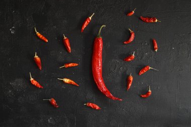Taze kırmızı kırmızı biber seti, siyah taş zemin üzerinde, üst görünüm düz, metin için kopyalama alanı ile