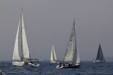 Bodrum, Türkiye. 15 Nisan 2018: Ünlü tatil beldesi Bodrum 'un kıyılarında, Ege Denizi' nin mavi sularında rüzgarlı havada yelken açan yelkenliler.