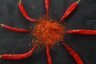 Yassı kırmızı acı biber, kırmızı biber taneleri ve siyah arkaplanda kırmızı biber tozu vardı..