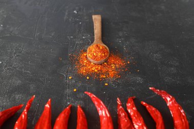 Ahşap kaşık baharatları ve kurutulmuş kırmızı biber arkaplanındaki kırmızı kırmızı kırmızı biber tozu. Üst tabakta bulunan kırmızı kırmızı biber tozu. Tayland baharatlı Asya yemekleri.