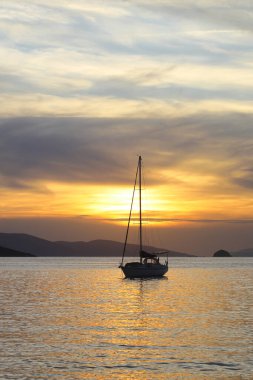 Günbatımında yalnız yelkenli. Turuncu güneşli atmosferik deniz manzarası. 