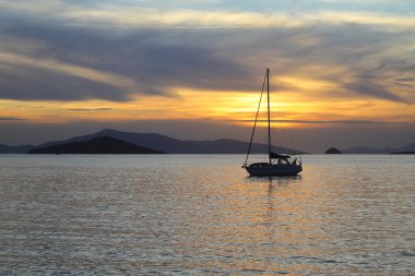 Günbatımında yalnız yelkenli. Turuncu güneşli atmosferik deniz manzarası. 