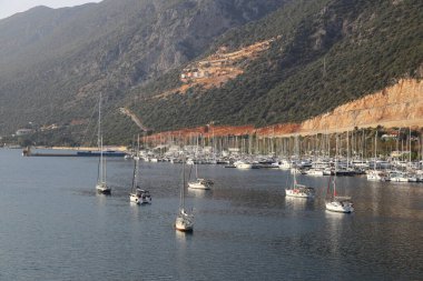 Kas, Türkiye. 15 Kasım 2021: Meddditera Denizi 'nde yatları olan güzel körfez. Kas Marina 'daki tekneler ve Türk Akdeniz kıyısındaki kayalık dağlar, popüler turizm beldesi. Deniz yatları dağların arka planında, tatil köyünde.