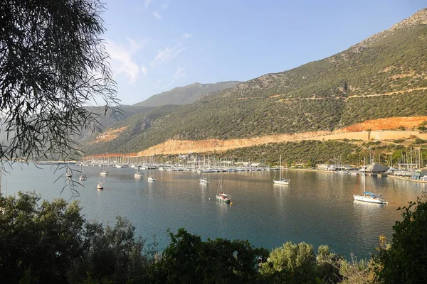 Kas, Türkiye. 15 Kasım 2021: Meddditera Denizi 'nde yatları olan güzel körfez. Kas Marina 'daki tekneler ve Türk Akdeniz kıyısındaki kayalık dağlar, popüler turizm beldesi. Deniz yatları dağların arka planında, tatil köyünde.
