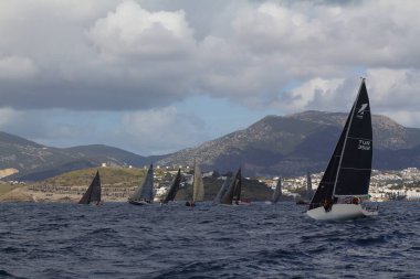 Bodrum, Hindi. 24 Mart 2018: Ege Denizi 'nin mavi sularında, ünlü tatil beldesi Bodrum' un kıyılarında yelkenliler rüzgarlı havada yelken açıyor.