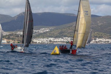 Bodrum, Hindi. 24 Mart 2018: Ege Denizi 'nin mavi sularında, ünlü tatil beldesi Bodrum' un kıyılarında yelkenliler rüzgarlı havada yelken açıyor.