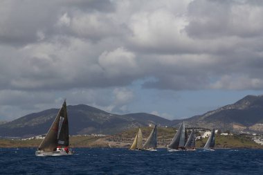Bodrum, Hindi. 24 Mart 2018: Ege Denizi 'nin mavi sularında, ünlü tatil beldesi Bodrum' un kıyılarında yelkenliler rüzgarlı havada yelken açıyor.