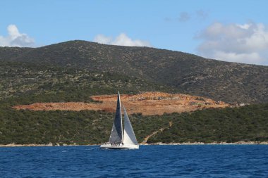 Bodrum, Hindi. 24 Mart 2018: Ege Denizi 'nin mavi sularında, ünlü tatil beldesi Bodrum' un kıyılarında yelkenliler rüzgarlı havada yelken açıyor.