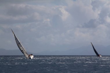 Bodrum, Hindi. 24 Mart 2018: Ege Denizi 'nin mavi sularında, ünlü tatil beldesi Bodrum' un kıyılarında yelkenliler rüzgarlı havada yelken açıyor.