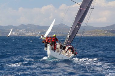 Bodrum, Hindi. 24 Mart 2018: Ege Denizi 'nin mavi sularında, ünlü tatil beldesi Bodrum' un kıyılarında yelkenliler rüzgarlı havada yelken açıyor.