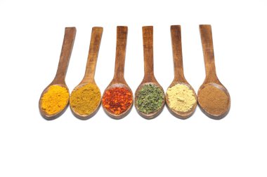Beyaz arka planda farklı baharatlar var. Doğu baharatları kaşıklarda, kırmızı biberler, köri tozu, tarçın tozu, nane tozu, renkli biber. Düz yatış, üst görünüm.