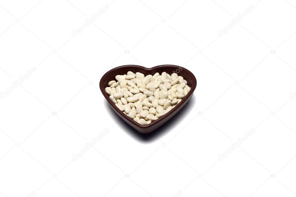 white kidney beans in a heart shaped bowl a on white background.Top view.
