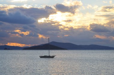 Günbatımında yalnız yelkenli. Turuncu güneşli atmosferik deniz manzarası