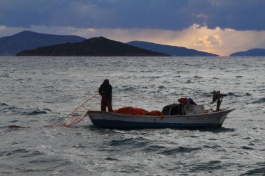 Bodrum, Hindi. 24 Mart 2021: Yağmurlu bir günde Ege Denizi 'nde küçük bir teknede balık tutmaya çalışan bir balıkçı.