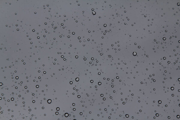 Rain drops on the glass in the spring afternoon. Close up of a window with rain drops falling down.The rain drops on household windows. Focus on rain drops. concept of sadness, frustration