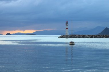 Gün ışığında deniz manzarası. Deniz feneri ve sahilde yelkenliler. Deniz kenti Turgutreis ve muhteşem güneş ışığı