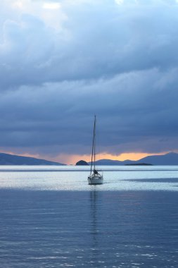 Günbatımında yalnız yelkenli. Yansımalı atmosferik deniz manzarası