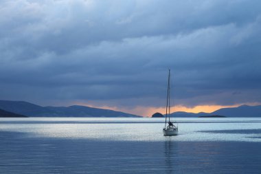 Günbatımında yalnız yelkenli. Yansımalı atmosferik deniz manzarası