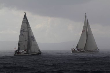 Bodrum, Hindi. 02 Mart 2019: Şiddetli yağmurda denizde yüzen yelkenliler. Yelkenliler Ege Denizi 'nin mavi sularında rüzgarlı havada yelken açarlar..  