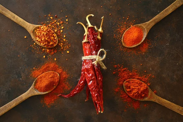 cayenne pepper on wooden spoon spices and dried chilli peppers background / group of red hot chilli powder on black plate top view ingredients table asian food spicy in thailand