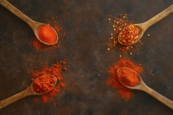 cayenne pepper on wooden spoon spices and dried chilli peppers background / group of red hot chilli powder on black plate top view ingredients table asian food spicy in thailand