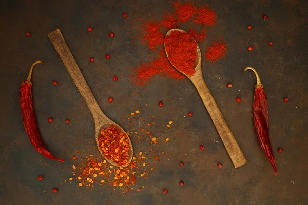 cayenne pepper on wooden spoon spices and dried chilli peppers background / group of red hot chilli powder on black plate top view ingredients table asian food spicy in thailand