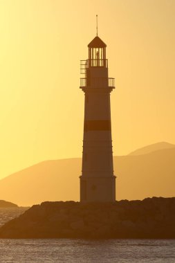 Gün batımında deniz manzarası. Sahildeki deniz feneri
