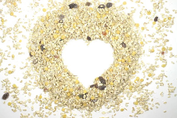 Yulaf ezmesi kalbi beyaz bir arkaplanda izole edilmiş ve bir yazı için yeri var. Bunting Heart sembolü. Mısır gevreğinin kalbi. Sağlıklı beslenme. Yulaf lapası yukardan vurulan kalp şeklinde.