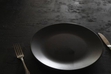 Karanlık taş masada boş siyah levha. Menü için yemek geçmişi, tarif. Masa ayarı. Flatlay, üst manzara. Restoran yemeği için maket.