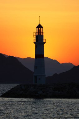 Gün ışığında deniz manzarası. Deniz feneri ve sahilde yelkenliler. Deniz kenti Turgutreis ve muhteşem güneş ışığı