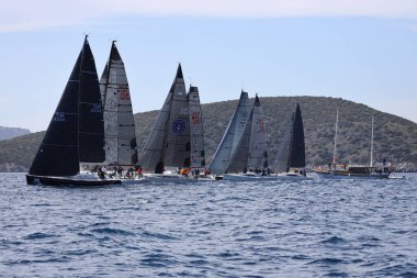 Bodrum, Hindi. 09 Nisan 2022: Yelkenliler Ege Denizi 'nin mavi sularında, ünlü tatil beldesi Bodrum' un kıyılarında rüzgarlı havada yelken açıyor.