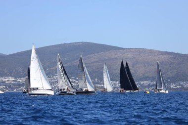 Bodrum, Hindi. 09 Nisan 2022: Yelkenliler Ege Denizi 'nin mavi sularında, ünlü tatil beldesi Bodrum' un kıyılarında rüzgarlı havada yelken açıyor.