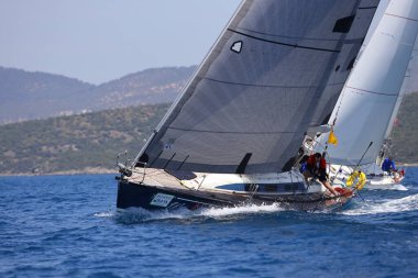 Bodrum, Hindi. 07 Mayıs 2022: Ege Denizi 'nin mavi sularında, ünlü tatil beldesi Bodrum' un kıyılarında yelkenliler rüzgarlı havada yelken açıyor.