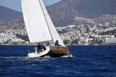 Bodrum, Hindi. 10 Nisan 2022: Yelkenliler Ege Denizi 'nin mavi sularında, ünlü tatil beldesi Bodrum' un kıyılarında rüzgarlı havada yelken açıyorlar..