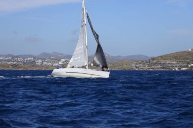 Bodrum, Hindi. 10 Nisan 2022: Yelkenliler Ege Denizi 'nin mavi sularında, ünlü tatil beldesi Bodrum' un kıyılarında rüzgarlı havada yelken açıyorlar..