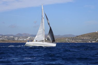 Bodrum, Hindi. 10 Nisan 2022: Yelkenliler Ege Denizi 'nin mavi sularında, ünlü tatil beldesi Bodrum' un kıyılarında rüzgarlı havada yelken açıyorlar..