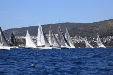 Bodrum, Hindi. 10 Nisan 2022: Yelkenliler Ege Denizi 'nin mavi sularında, ünlü tatil beldesi Bodrum' un kıyılarında rüzgarlı havada yelken açıyorlar..