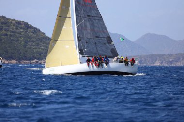 Bodrum, Hindi. 10 Nisan 2022: Yelkenliler Ege Denizi 'nin mavi sularında, ünlü tatil beldesi Bodrum' un kıyılarında rüzgarlı havada yelken açıyorlar..