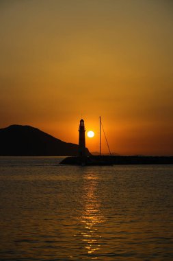 Gün ışığında deniz manzarası. Deniz feneri ve sahilde yelkenliler. Deniz kenti Turgutreis ve muhteşem güneş ışığı
