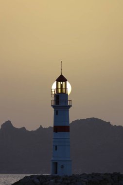 Gün ışığında deniz manzarası. Deniz feneri ve sahilde yelkenliler. Deniz kenti Turgutreis ve muhteşem güneş ışığı