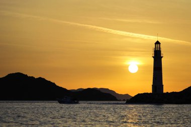 Gün ışığında deniz manzarası. Deniz feneri ve sahilde yelkenliler. Deniz kenti Turgutreis ve muhteşem güneş ışığı