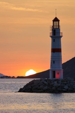 Gün ışığında deniz manzarası. Deniz feneri ve sahilde yelkenliler. Deniz kenti Turgutreis ve muhteşem güneş ışığı
