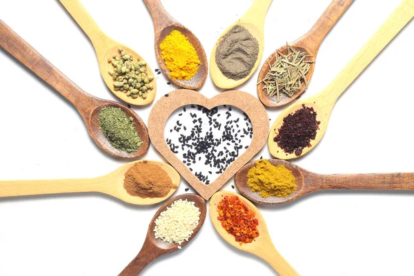 Different kind of spices on a white background. Oriental spices in spoons, red peppers, curry powder, cinnamon powder, mint powder, sumac, sesame, black cumin, . Flat lay, top view. Heart Shape.