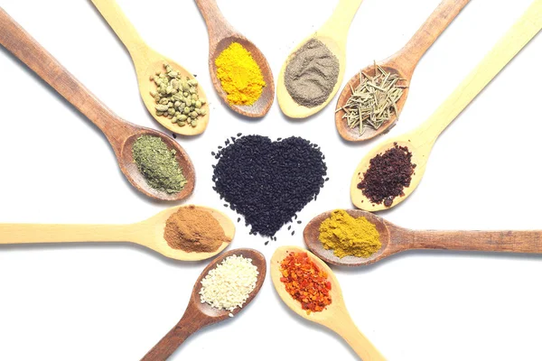 Different kind of spices on a white background. Oriental spices in spoons, red peppers, curry powder, cinnamon powder, mint powder, sumac, sesame, black cumin, . Flat lay, top view. Heart Shape.